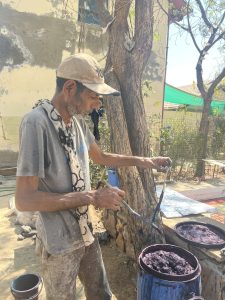 Mansukhbhai tests out the strength of the color. 