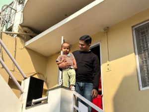 A father and son wave to the camera from the top of a staircase.